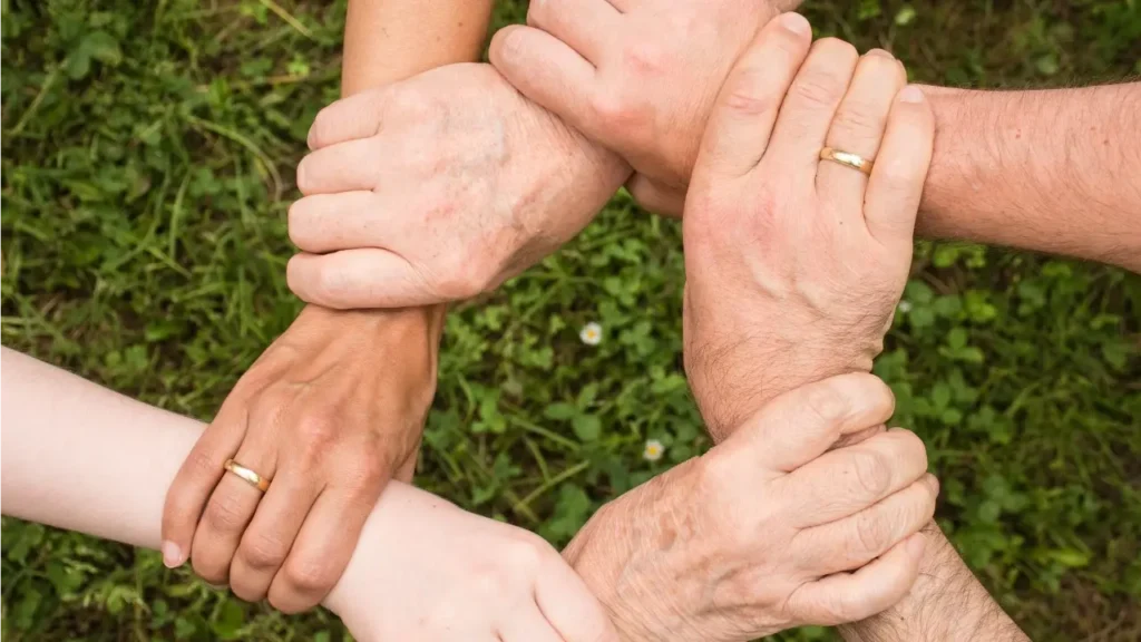 Fotografia de varias mão, uma segurando a outra pelo punho