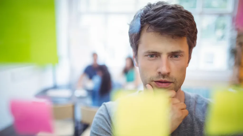 Fotografia de um homem encarando um painel com varias informações